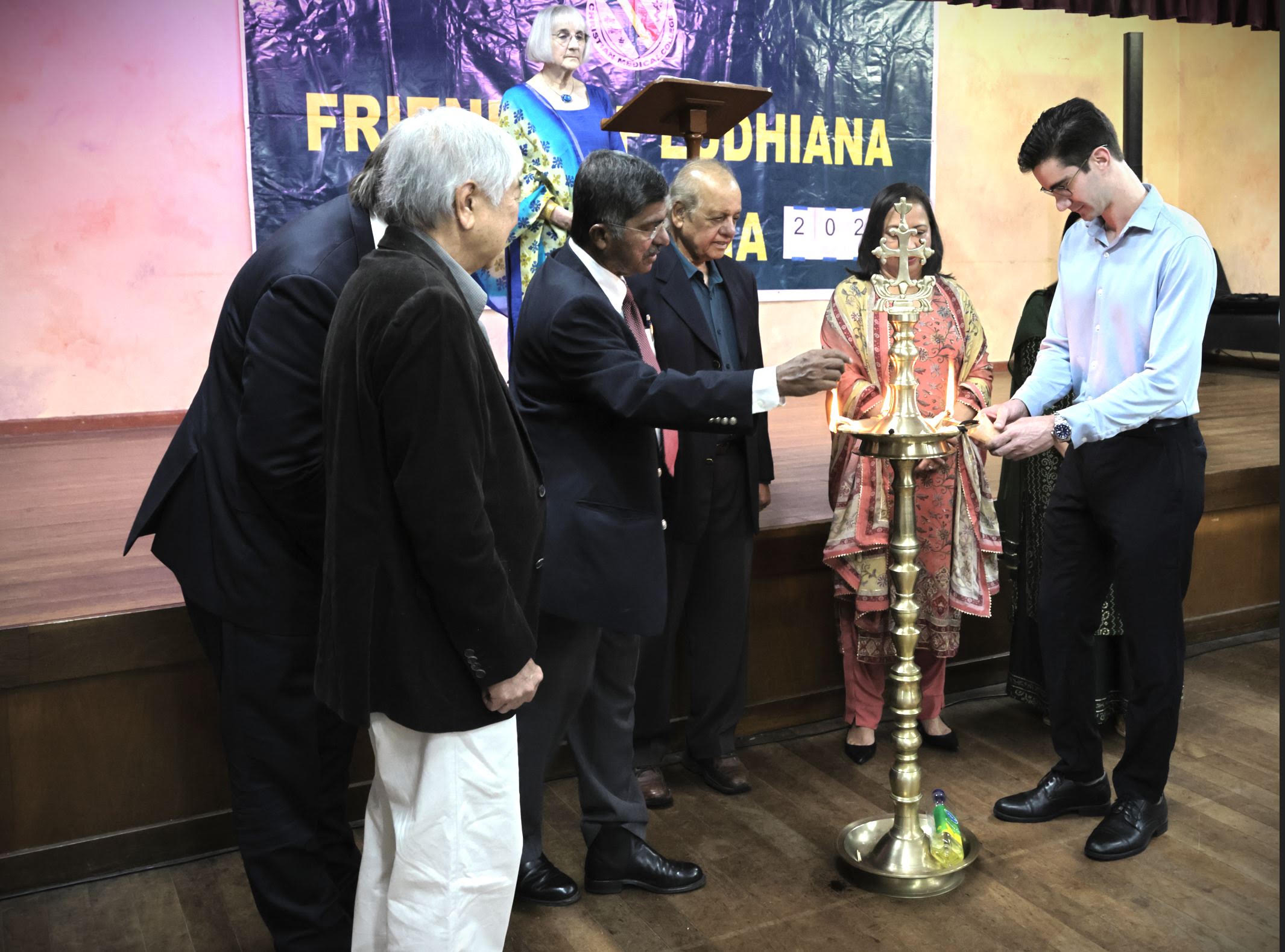Guests lighting the brass lamp beneath the Friends of Ludhiana banner